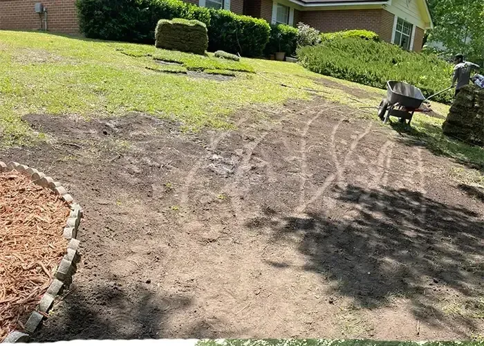 Bare, prepped dirt ground in a front yard before landscaping, brick house behind