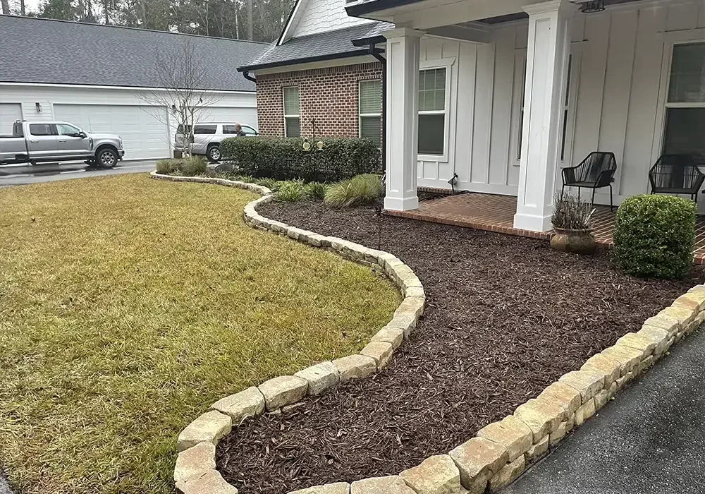 Front entry with curved landscape edging, dark mulch bed, and decorative stone border